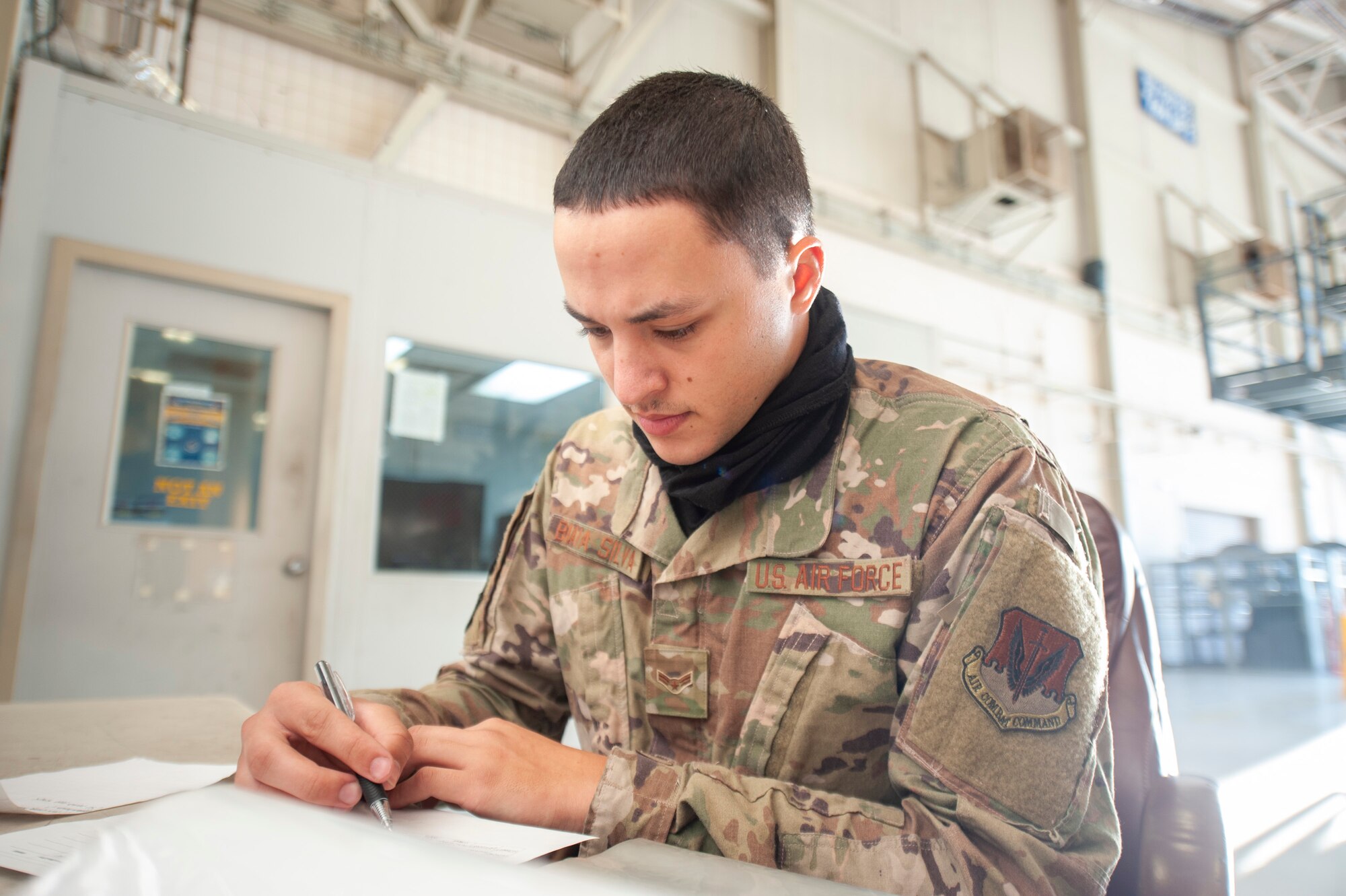 A photo of an Airman writing on a paper log.