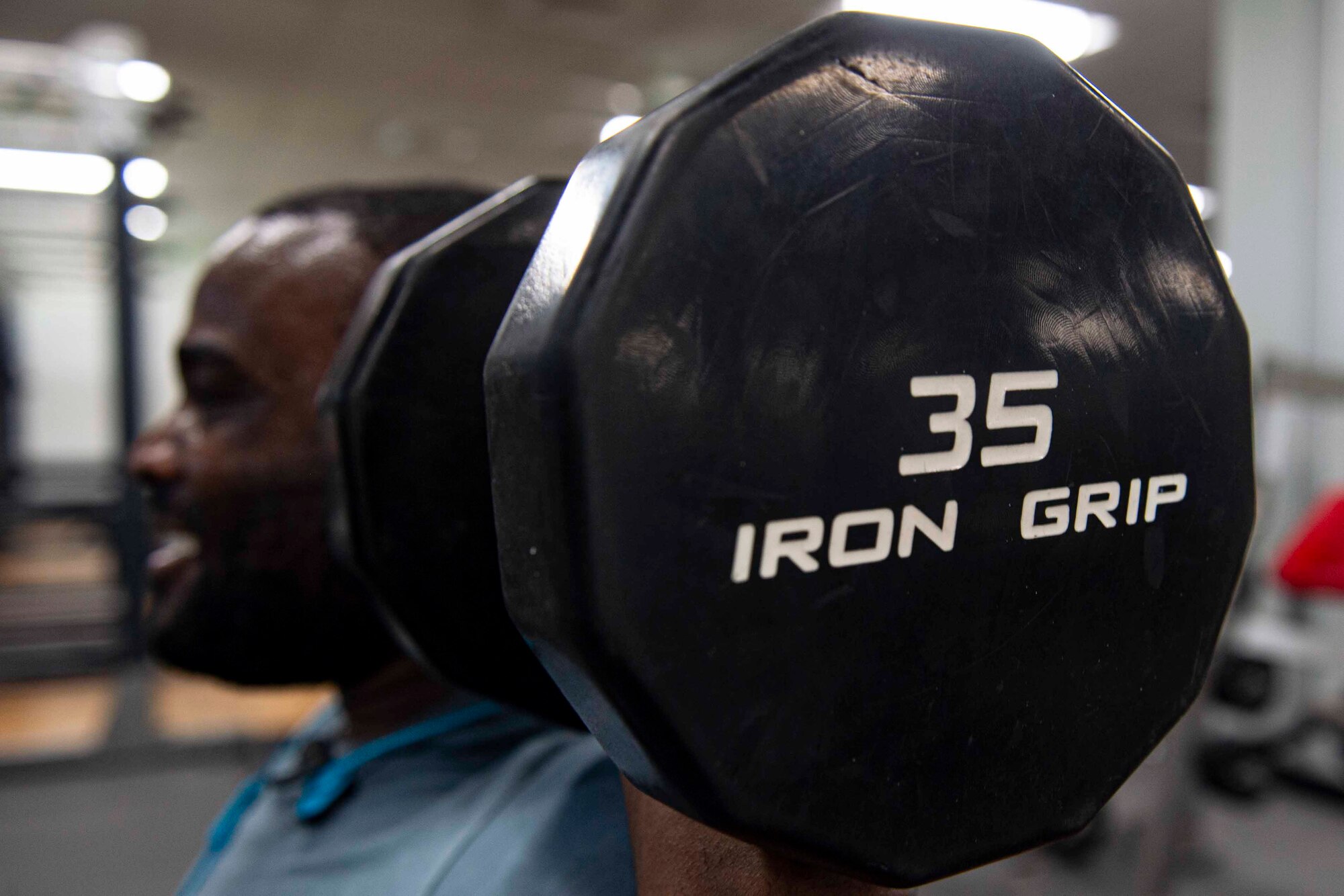 Photo of an Airman performing a dumbbell shoulder press.