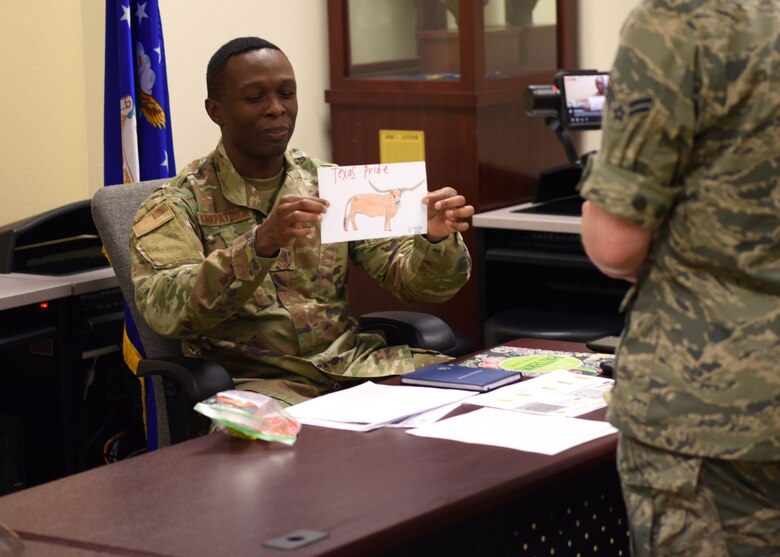 U.S. Air Force Airman 1st Class Michael Bowman, 17th Training Wing broadcast journalist, films Chief Master Sgt. Lavor Kirkpatrick, 17th TRW command chief, displaying a drawing made for members of Goodfellow during the COVID-19 Virtual Town Hall on Goodfellow Air Force Base, Texas, April 29, 2020. San Angelo supported Goodfellow with snacks, drawings, and even masks. (U.S. Air Force photo by Airman 1st Class Ethan Sherwood)