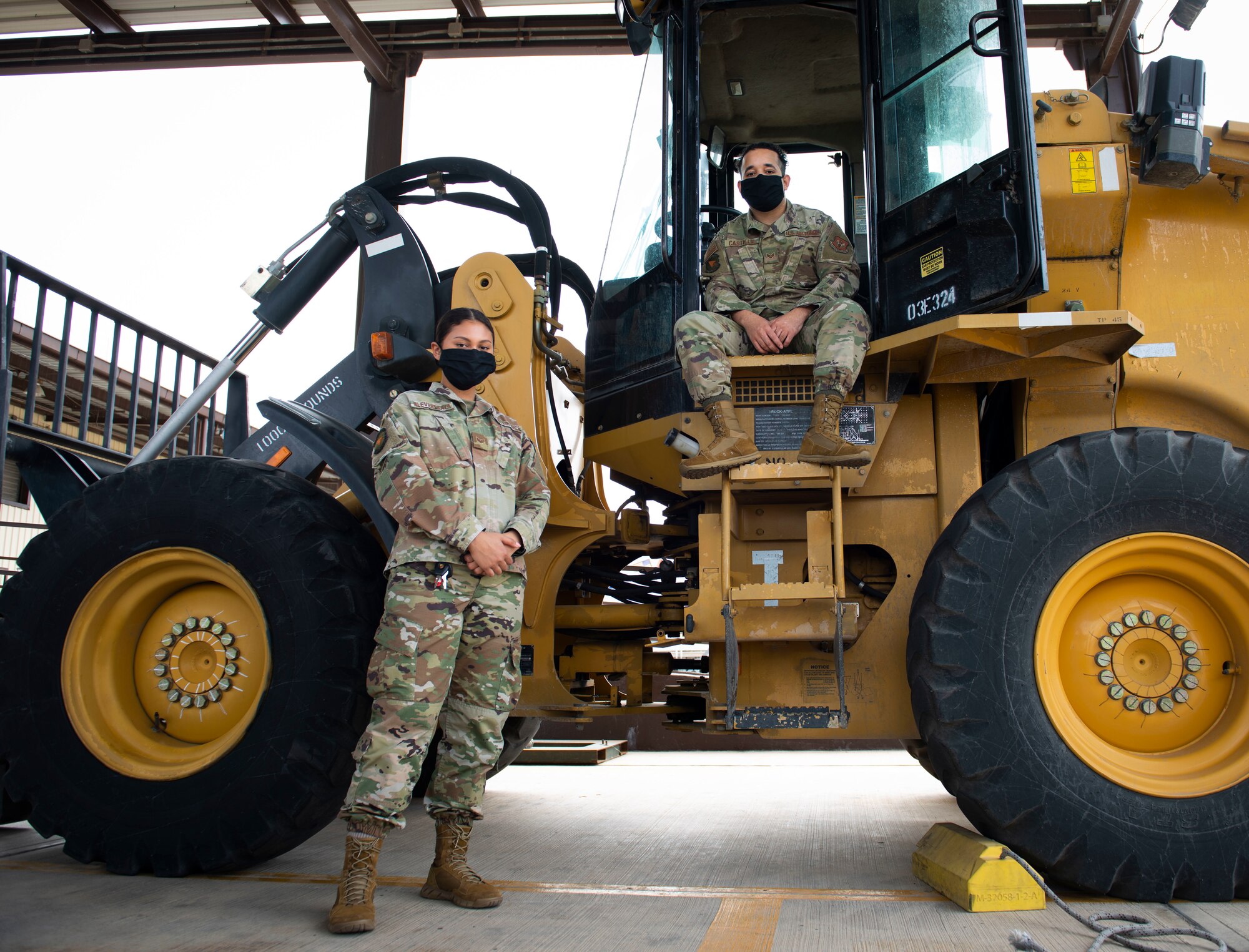 Photo of two Airmen posing by a 10K forklift