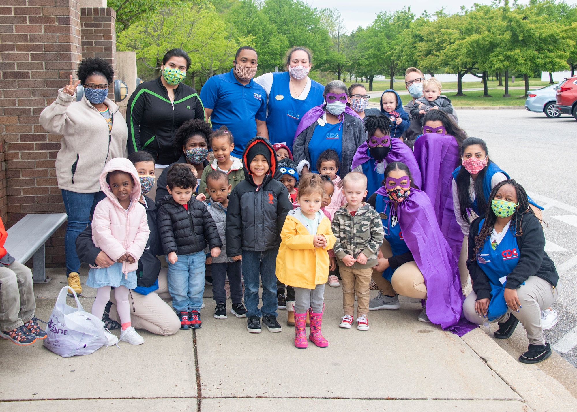 Child-care providers and children from Child Development Center 2 stand together after the Month of the Military Child parade on Joint Base Andrews, Md., April 24, 2020. Some of the providers are wearing purple as a visible way to show support and thank military youth for their strength and sacrifices. (U.S. Air Force photo by Staff Sgt. Jared Duhon)