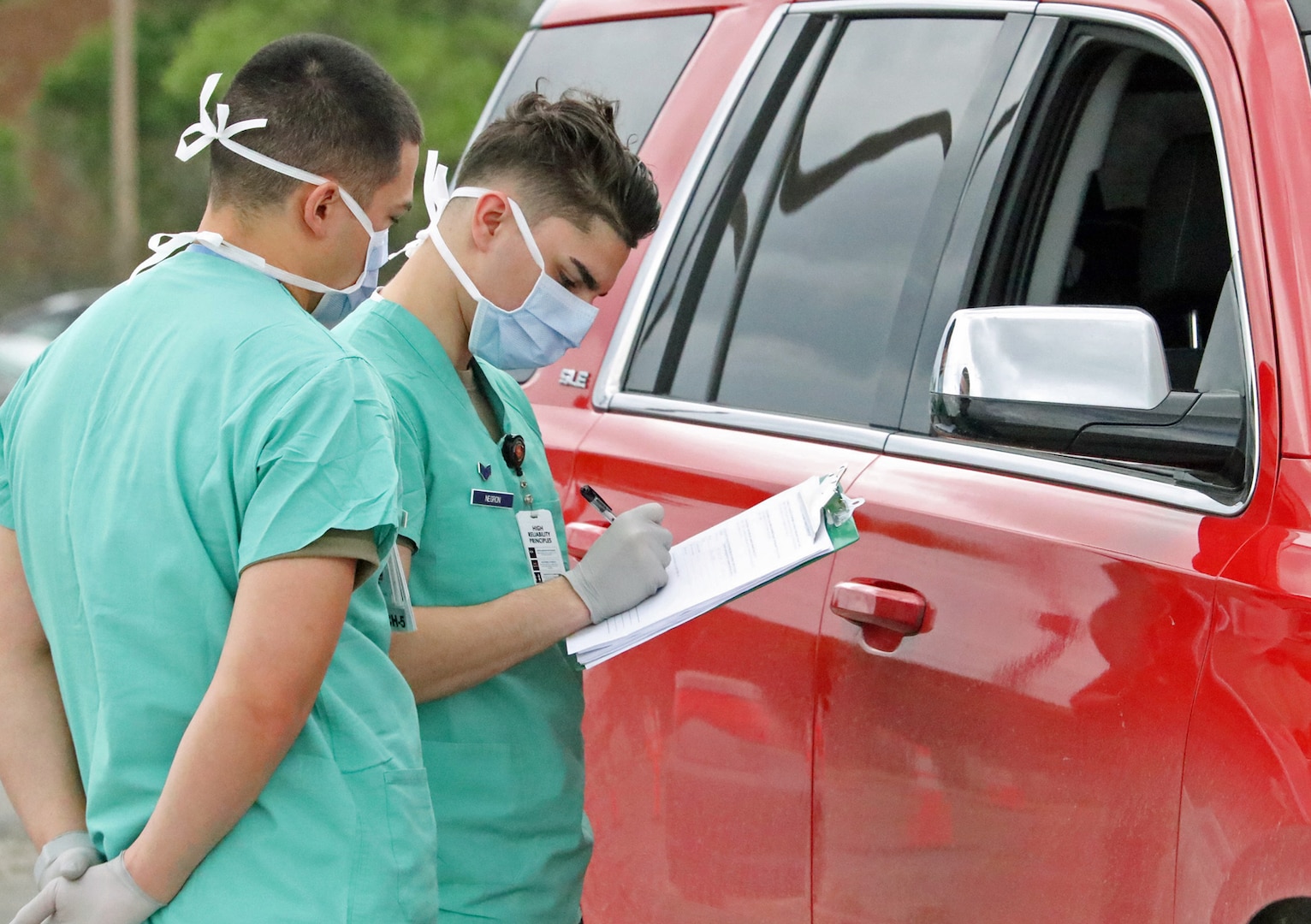 Senior Airman Robert Wolshlager (left) and Senior Airman Christian Negrón (right) conduct drive-thru COVID-19 screening at Brooke Army Medical Center's designated screening area March 17.