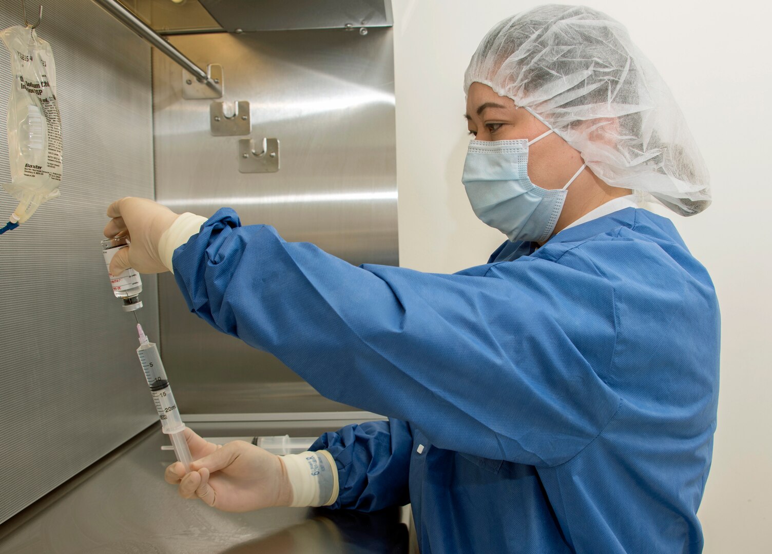 Michelle Mendoza, pharmacy technician, reconstitutes the remdesivir research drug under an intravenous hood at Brooke Army Medical Center