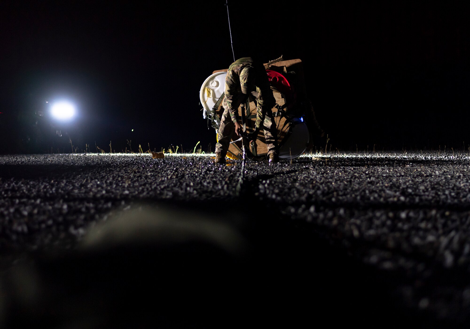 A photo of an Airman detaching a parachute from cargo