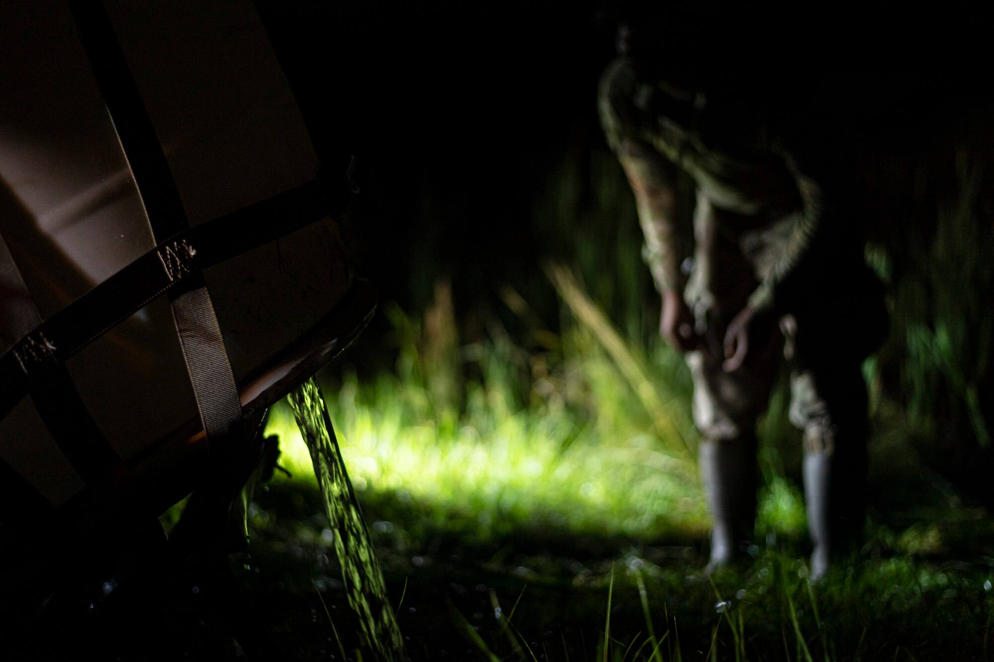 A photo of Airmen draining water from plastic drums
