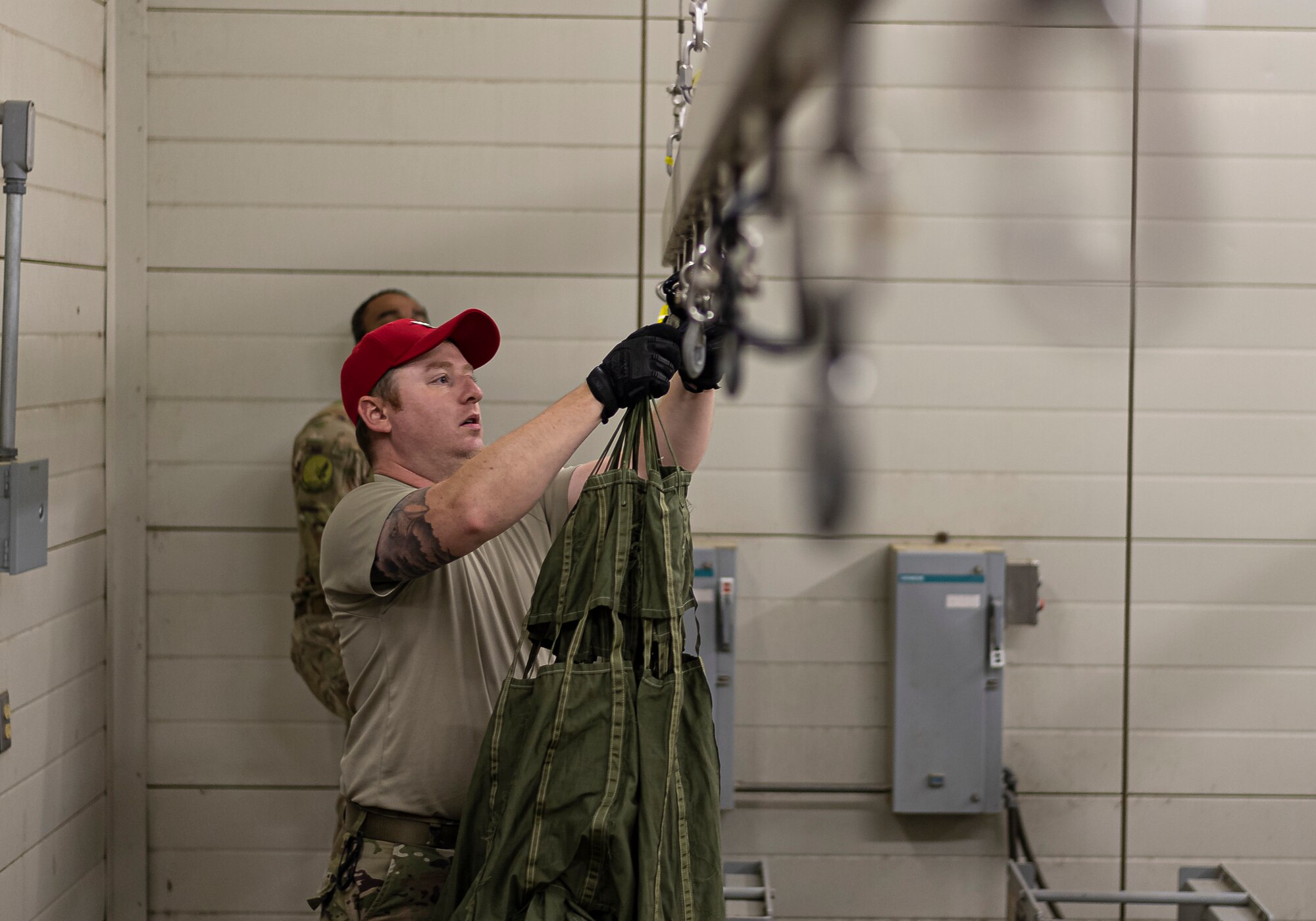 A photo of an Airman attaching a parachute to a drying rack