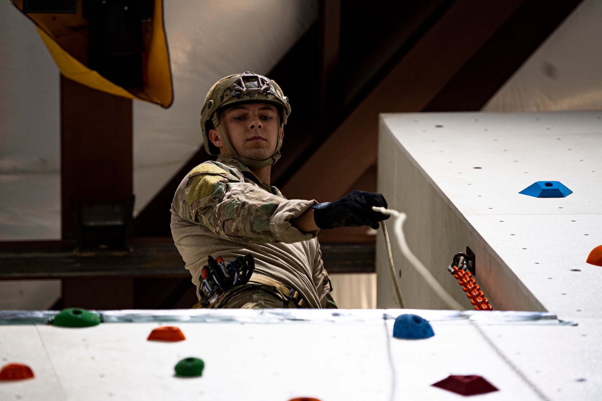 A photo of an Airman drops a rope down a climbing wall