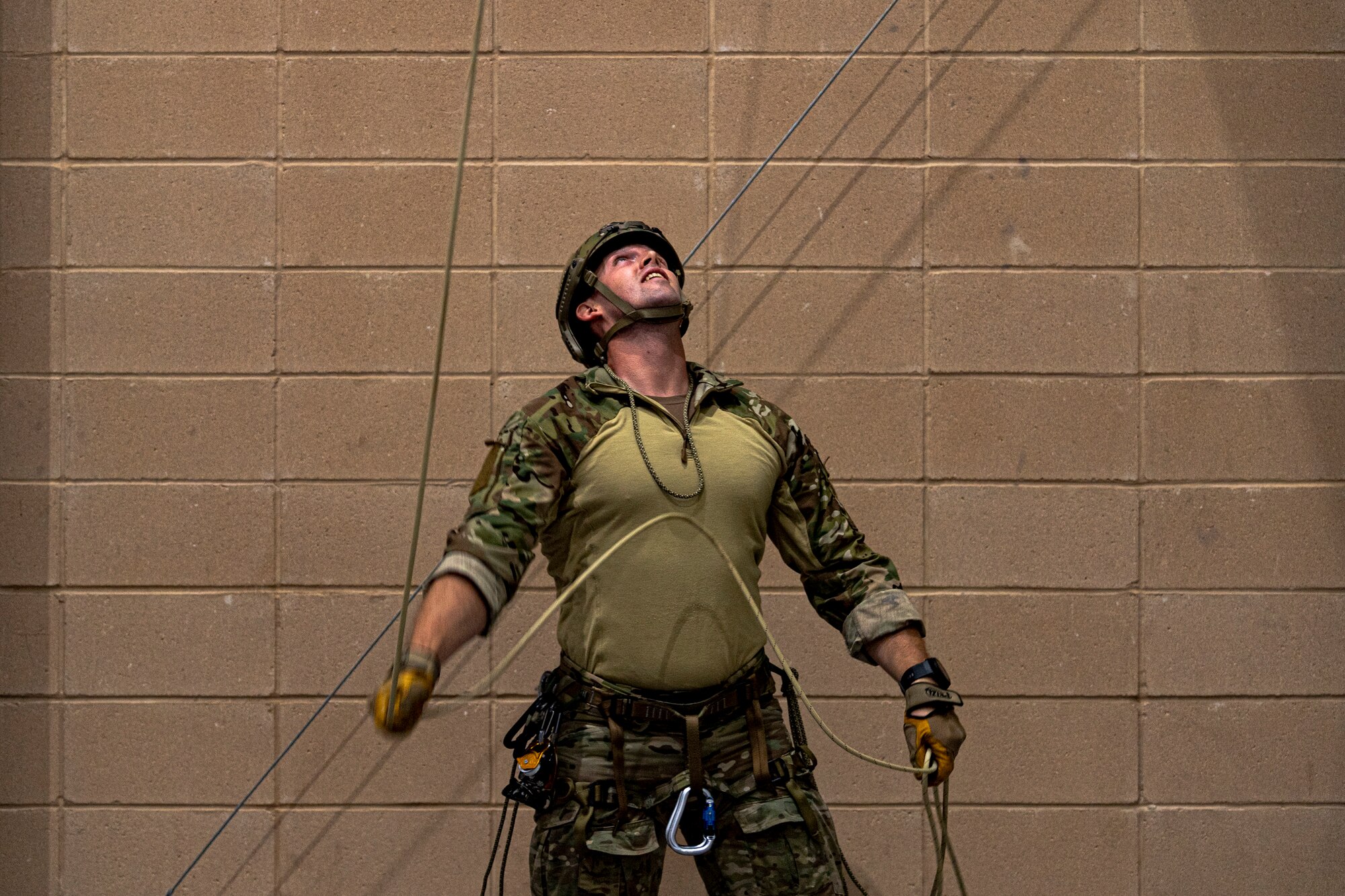 A photo of an Airman pulling a rope off a climbing wall