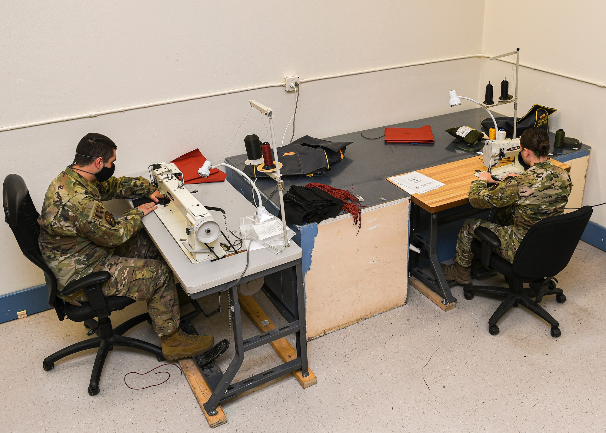 photo of two Airmen working on sewing machines