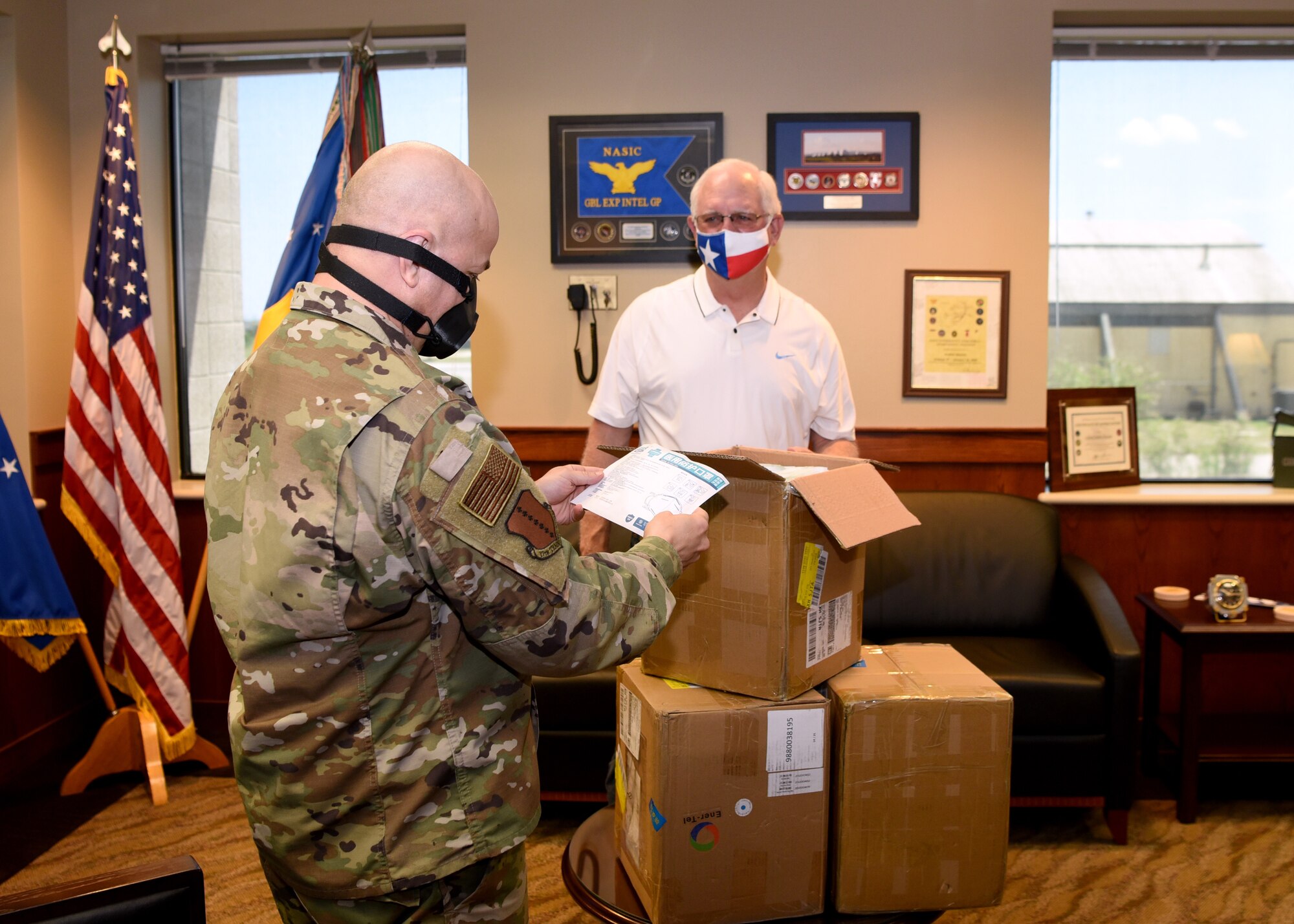 U.S. Air Force Col. Andres Nazario, 17th Training Wing commander, and San Angelo Military Advisor Group Co-Chair, Mike Boyd, unpack a donated box of disposable surgical masks inside the Norma Brown building on Goodfellow Air Force Base, Texas, April 28, 2020. Boyd and his wife delivered over 2,100 disposable surgical masks to the 17th Training Wing donated by Managing Partner of Principal LED, Bryan Vincent, and Ener-Tel Owner, Scott Wisniewski. (U.S. Air Force photo by Airman 1st Class Abbey Rieves)