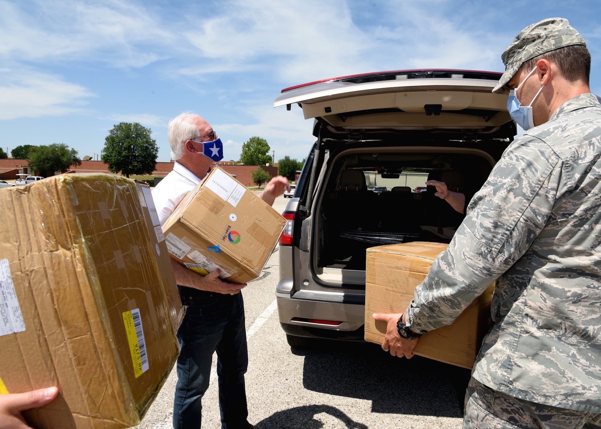 San Angelo Military Advisor Group Co-Chair, Mike Boyd, and U.S. Air Force Airmen from the 17th Training Wing unpack boxes of disposable surgical masks in front of the Norma Brown building on Goodfellow Air Force Base, Texas, April 28, 2020. The masks donated were a token of appreciation and demonstrate the tight-knit bond between the San Angelo Community and Goodfellow. (U.S. Air Force photo by Airman 1st Class Abbey Rieves)