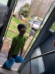 A boy on a school bus smiles after receiving bags of lunch.