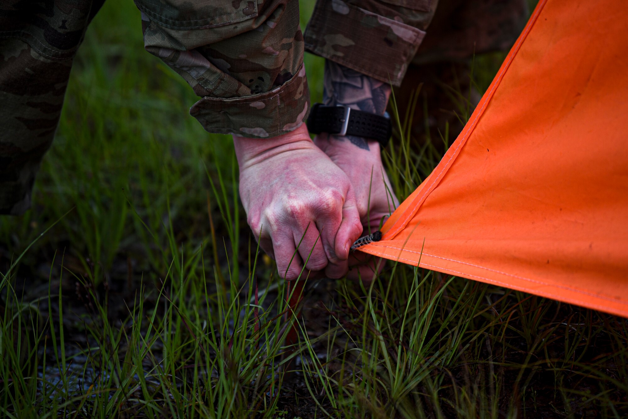 A photo of an Airman securing a marker to the ground