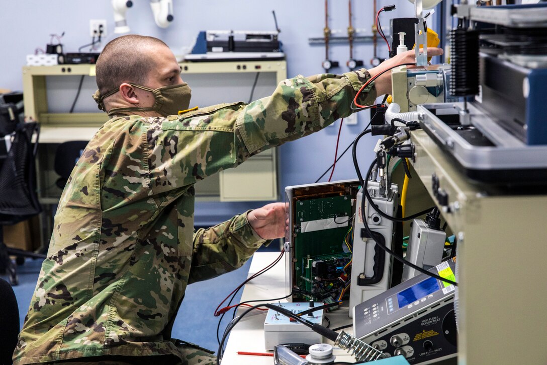 A soldier conducts service maintenance on a ventilator.