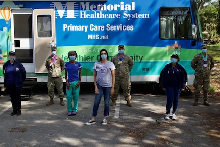 Florida National Guard service members and Memorial Healthcare System employees take a photo outside their command center after presenting donated and decorated medals from local children.