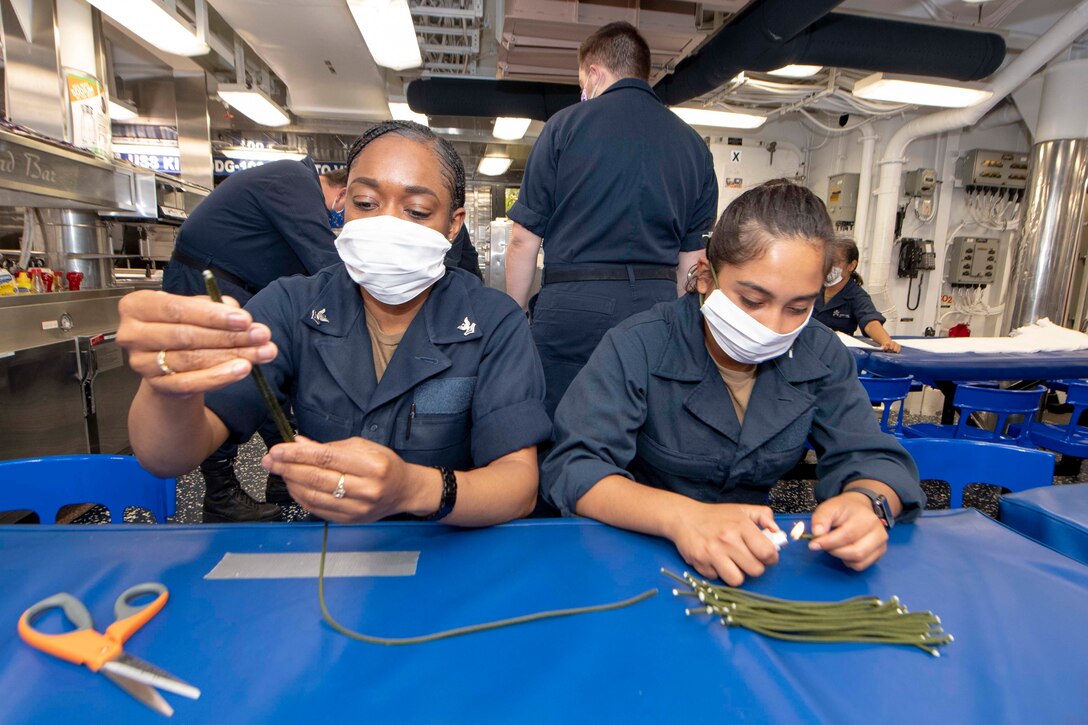 Sailors cut paracord to make straps for face masks.