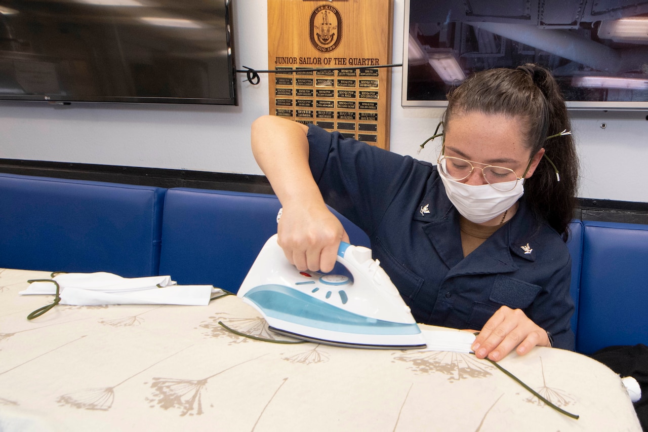 A sailor irons fabric used to make face masks.