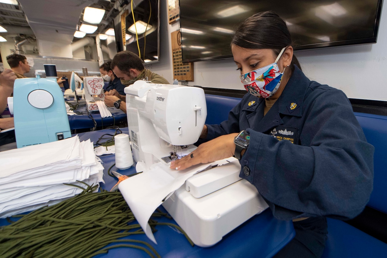 A Navy chief sews face masks.