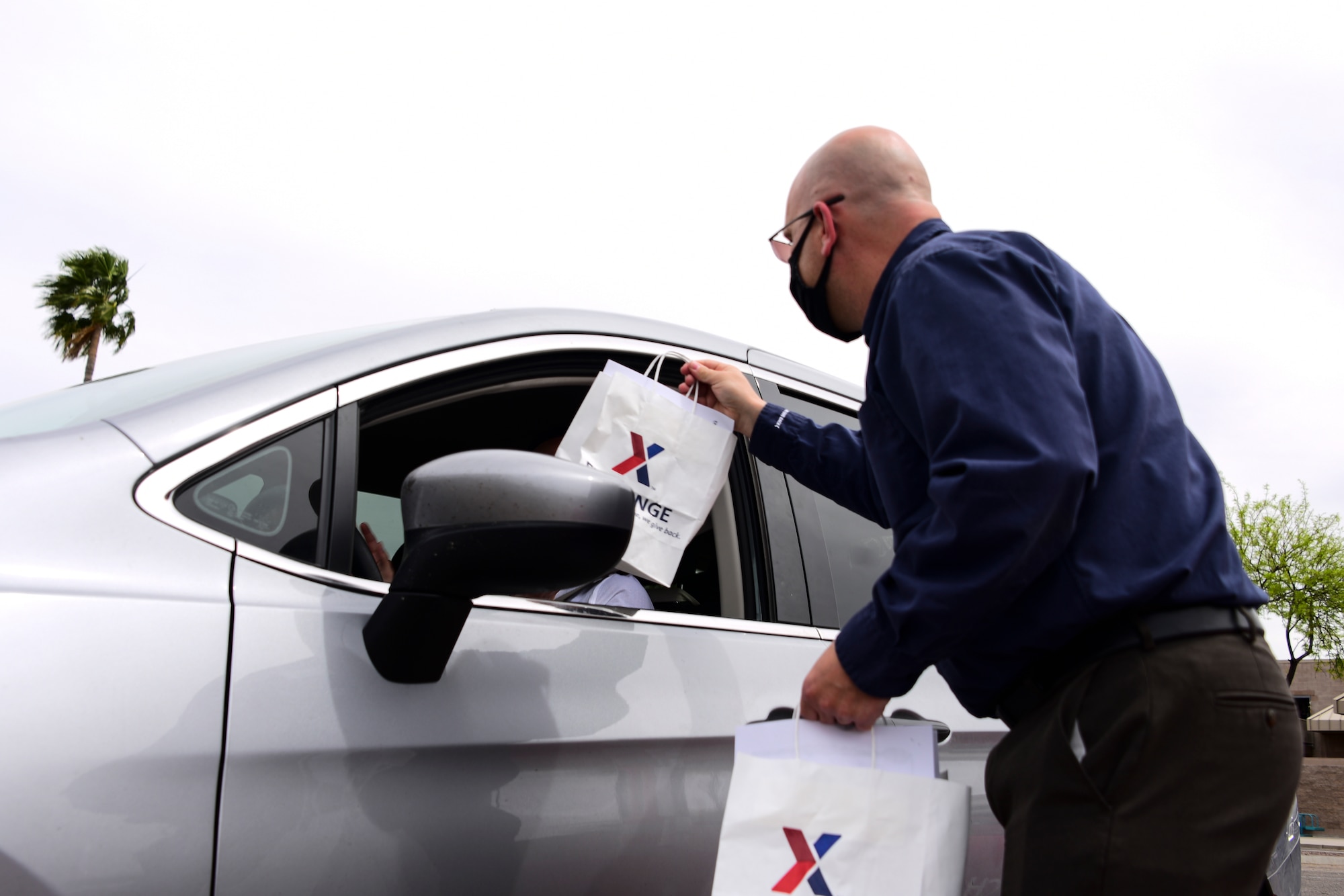 A photo of an AAFES employee giving gift bags to a military child
