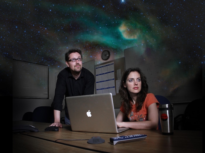 Mike Cushing and Amy Mainzer of JPL in a conference room at the California Institute of Technology in Pasadena. This is a dramatized image, enhanced with a starry sky, illustrating the mood during what astronomers call remote observing.