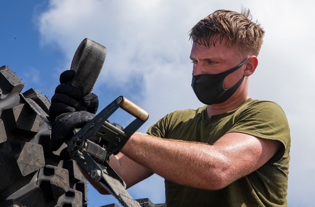 Male wearing a face mask works on a piece of equipment outdoors.