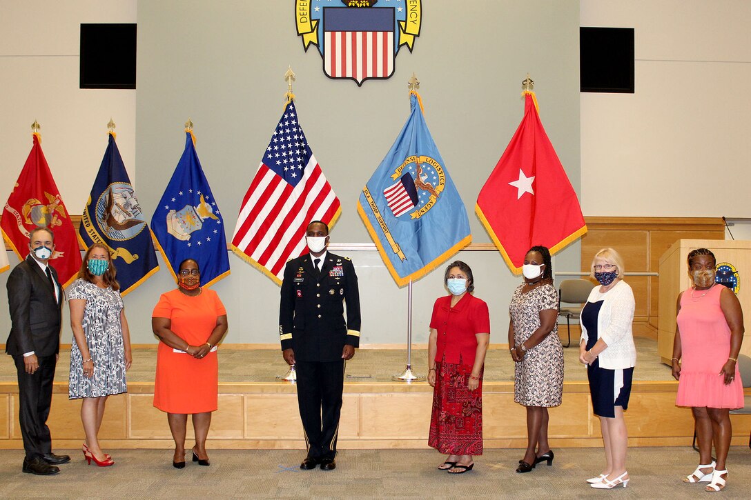 A group of people stand socially distanced during a civilian retirement ceremony.