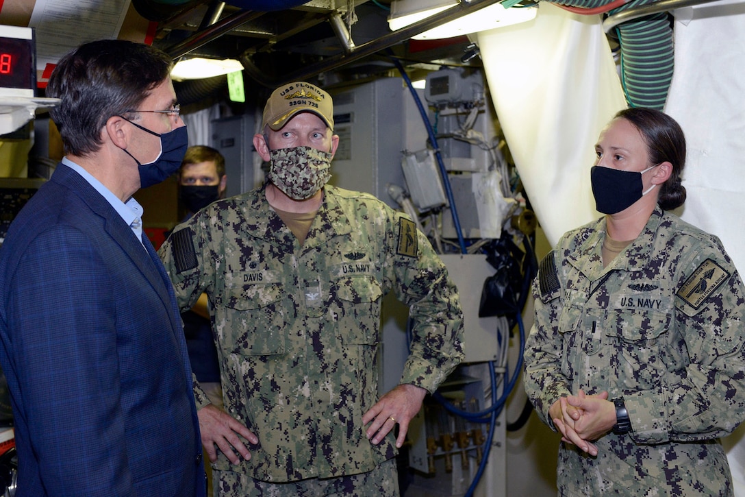 Defense Secretary Dr. Mark T. Esper talks with two sailors. All wear face masks.