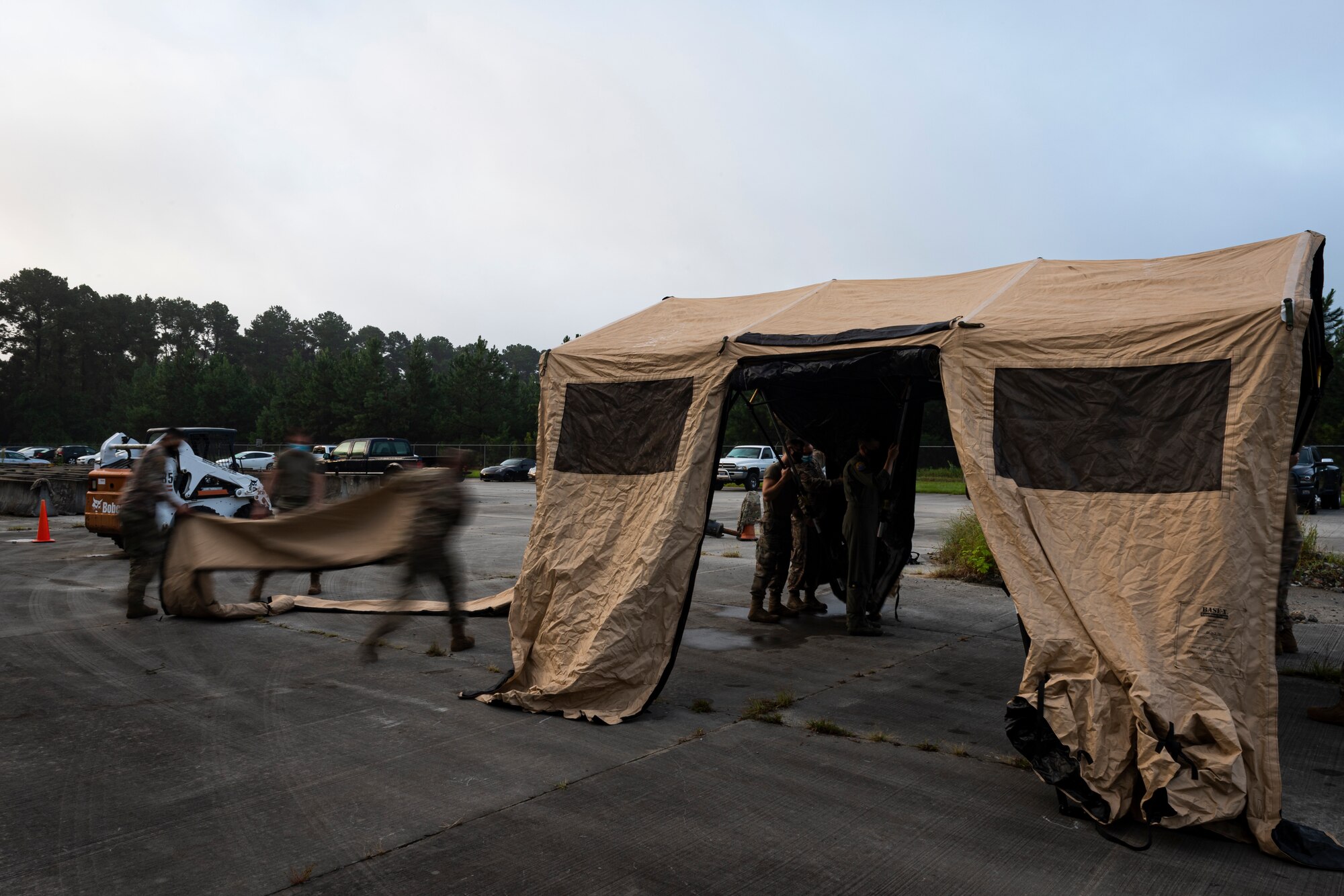 A photo of Airmen putting up a folding frame shelter.