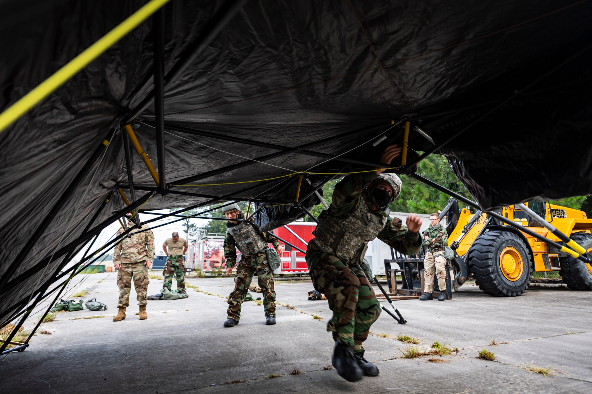 A photo of Airmen putting up a folding frame shelter.