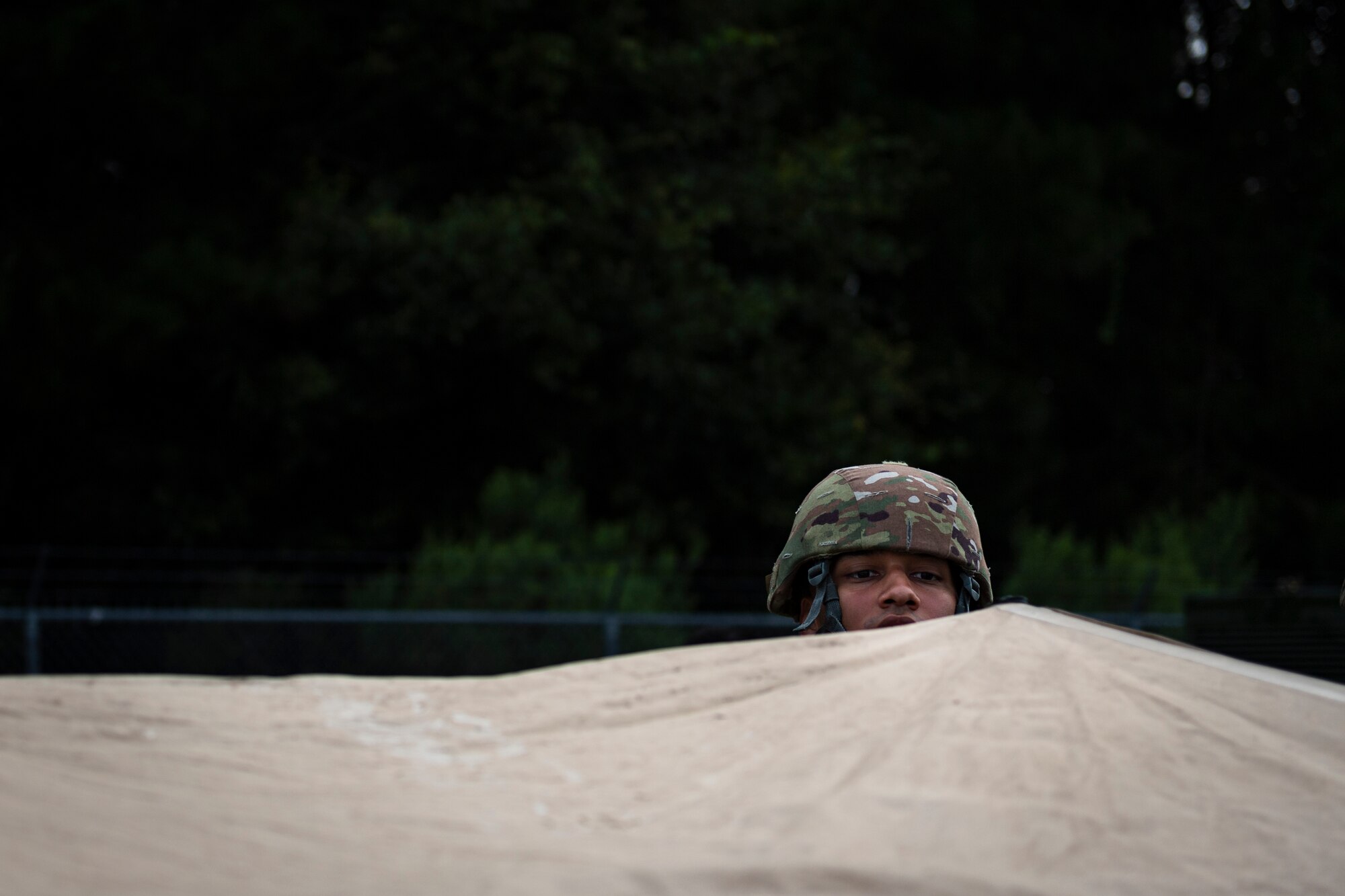 A photo of an Airman inspecting a folding frame shelter.