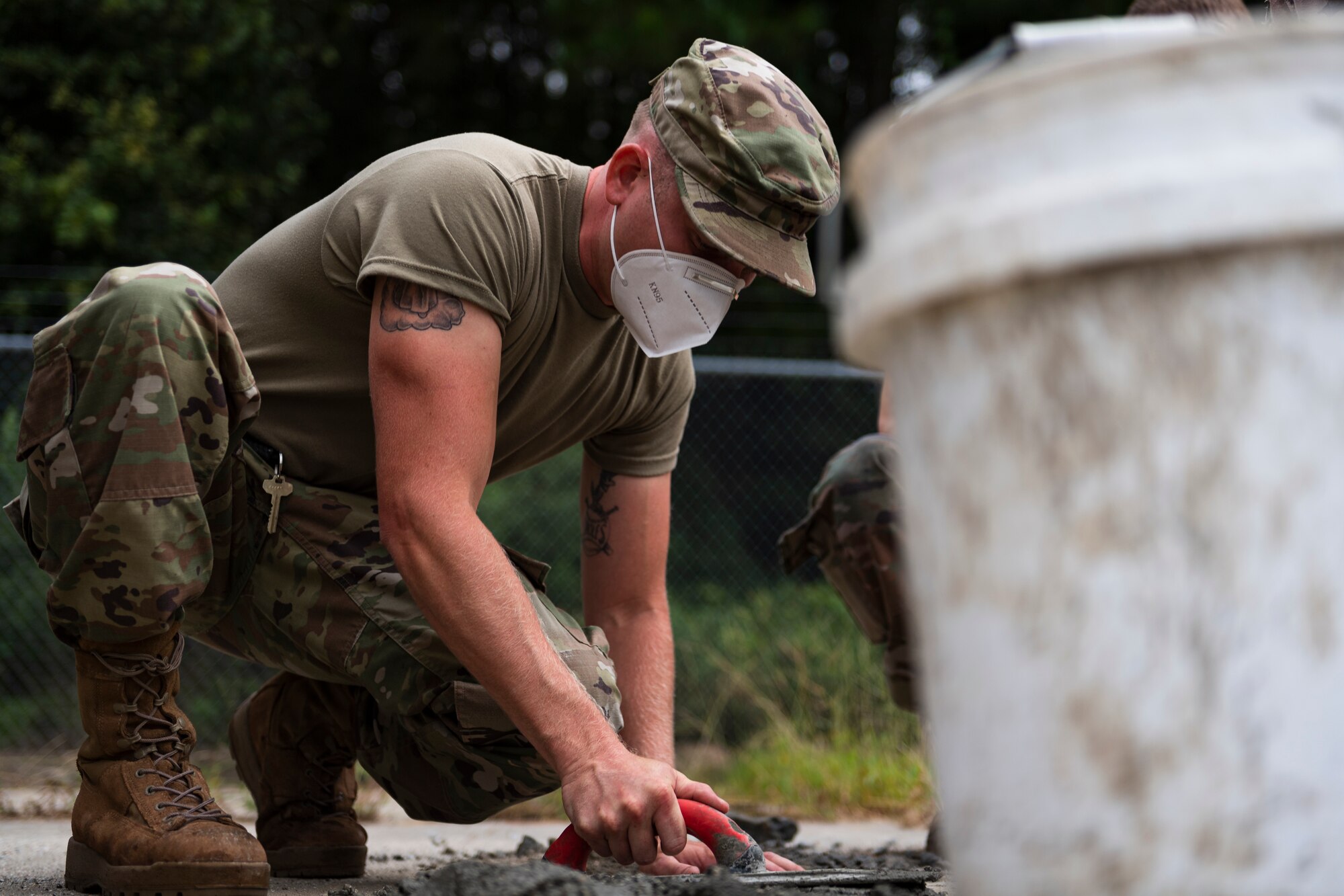 A photo of an Airman demonstrating appropriate procedure for finishing concrete.