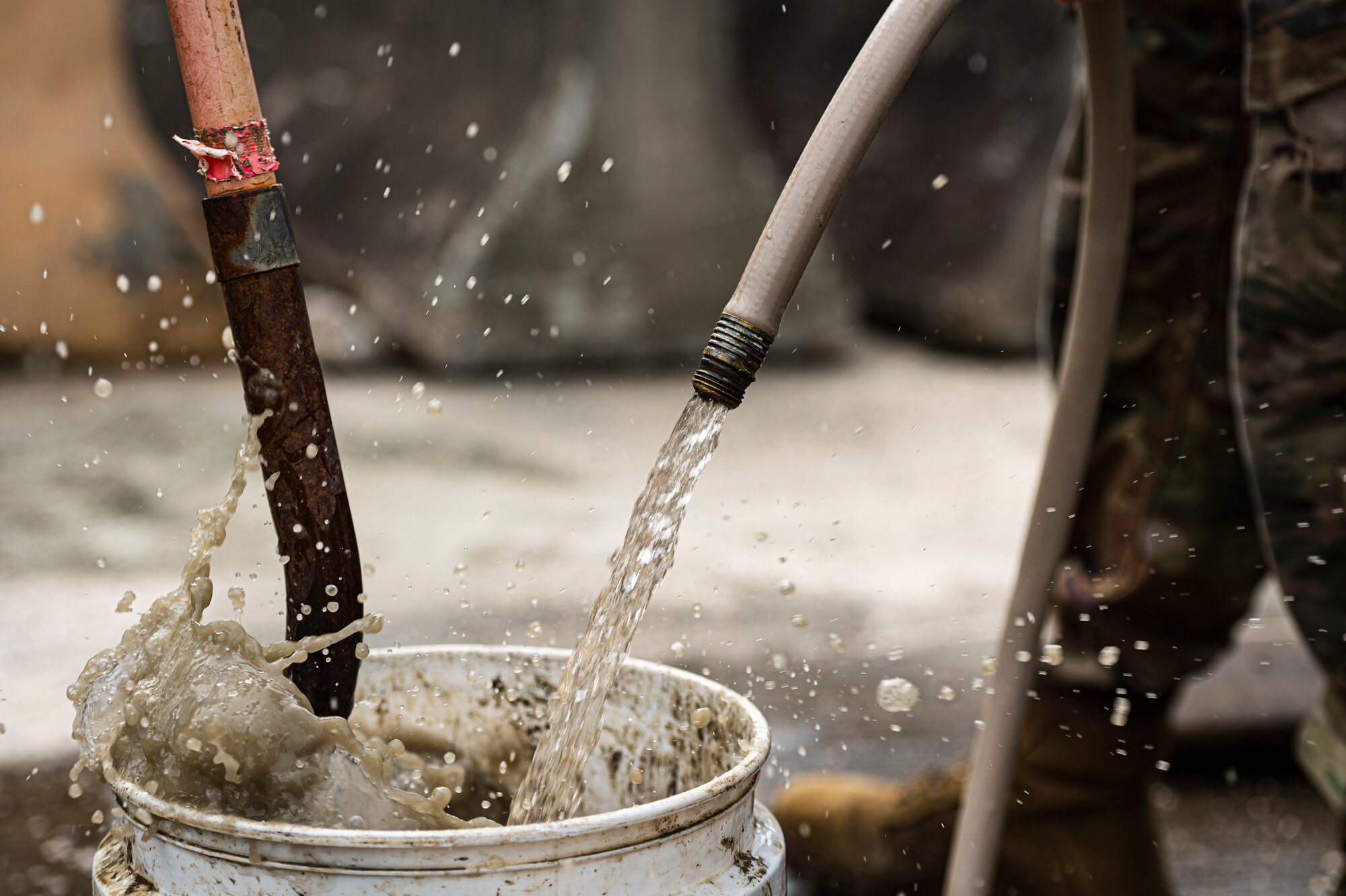 A photo of Airmen rinsing runway repair tools after pouring concrete