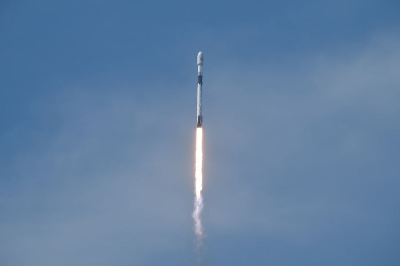 A rocket travels through a blue sky.