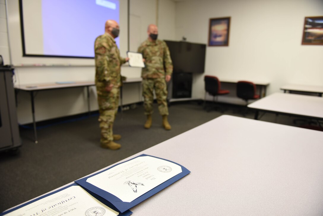 Tech. Sgt. Nazareth Oliver, 14th Operational Medical Readiness Squadron Aerospace and Operational Physiology Flight technician, receives his certification from Chief Master Sgt. Trevor James, 14th Flying Training Wing command chief July 16, 2020, after completing the Additional First Sergeant Symposium on Columbus Air Force Base, Miss. All of the curriculum for the symposium was given to the Columbus AFB First Sergeants running the program by the Air Force First Sergeant Academy. (U.S. Air Force photo by Senior Airman Keith Holcomb)