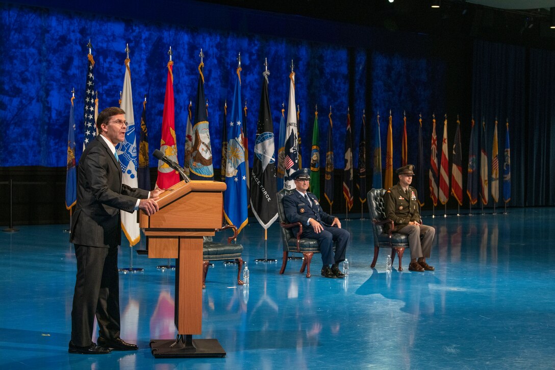 Defense Secretary Dr. Mark T. Esper speaks at a lectern; two others sit in chairs to the right.