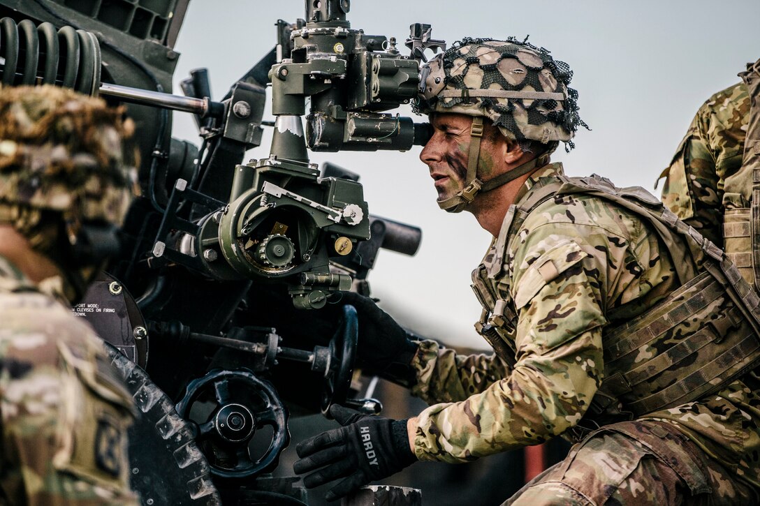A soldier looks through a weapon scope.