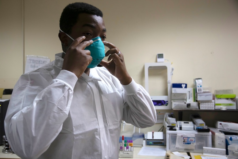 U.S. Army Reserve Sgt. Christopher Garrett, a lab technician with the 18th Field Hospital, Joint Expeditionary Base Little Creek-Fort Story, Virginia, dons his personal protective equipment before demonstrating the steps of a COVID-19 test  on Camp Buehring, Kuwait, July 30, 2020. The U.S. Army uses modern techniques and technology to mitigate the spread of COVID-19.(Photo by U.S. Army Reserve Staff Sgt. Christopher Osburn)