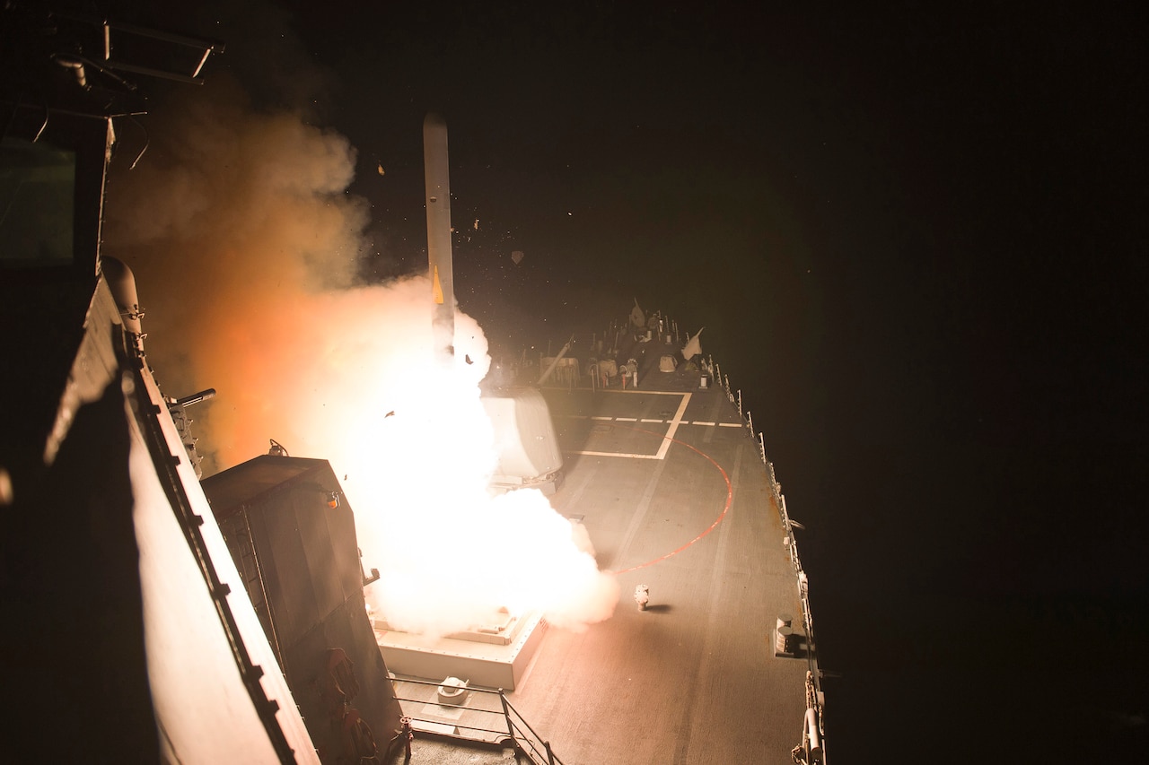 Ship fires missile at night.