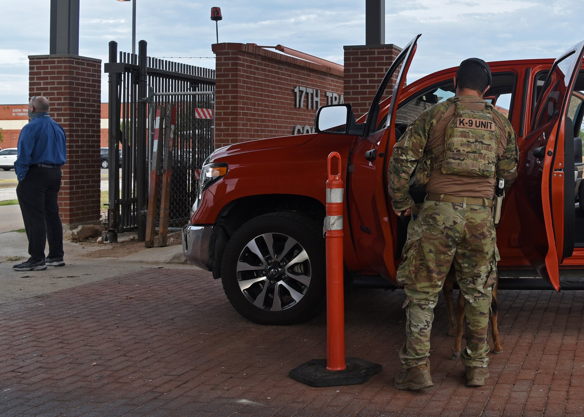 U.S. Air Force Staff Sgt. Nicholas Suitonu, 17th Security Forces Squadron military working dog handler, allows his K-9 to search while the vehicle driver waits during a vehicle inspection at The North Gate’s entry control point onto Goodfellow Air Force Base, Texas, Aug. 3, 2020. Vehicle inspections were led daily and at random intervals, despite COVID-19.  COVID-19 has not weakened our security posture in any way. (U.S. Air Force photo by Airman 1st Class Abbey Rieves)