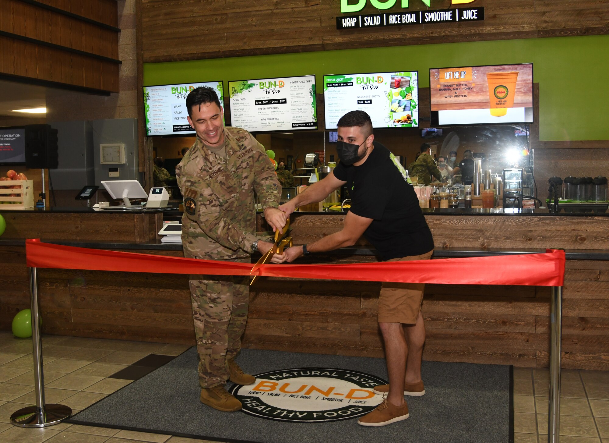 Men cut a ribbon at a ceremony.