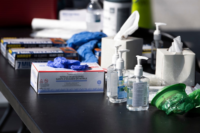 A table holds hand sanitizer, latex gloves and other medical supplies.