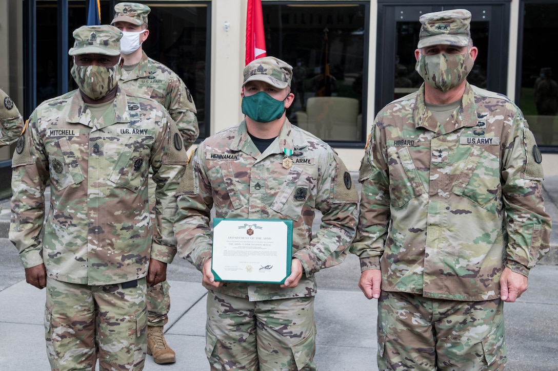 Three soldiers stand side by side while the soldier in the middle shows a certificate.