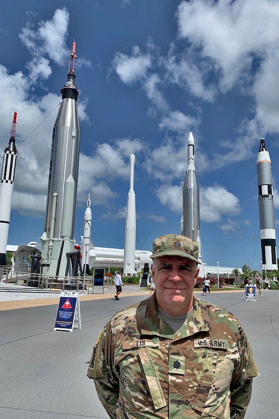 U.S. Army Reserve Lt. Col. Pat Lis stands in front of the “Rocket Garden” attraction at the Kennedy Space Center Visitor Complex in Florida. The Rocket Garden represents rockets from NASA’s Mercury, Gemini and Apollo programs including; the Saturn 1B, Delta, Juno I, Juno II, Gemini-Titan II, Mercury-Redstone and Mercury-Atlas rockets.