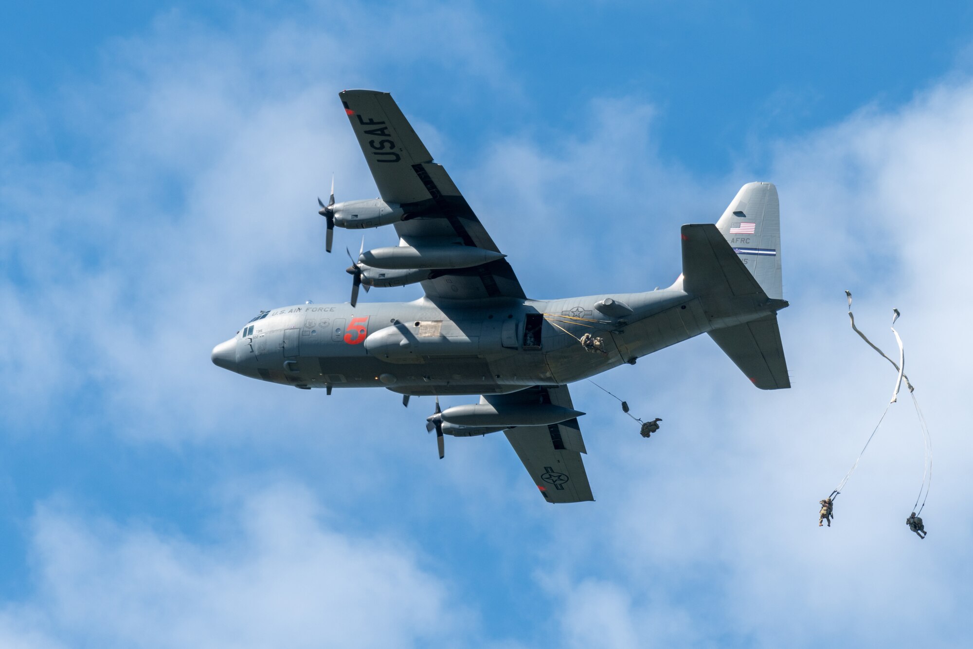 C-130 plane drops Army soldiers out of the back using parachutes.