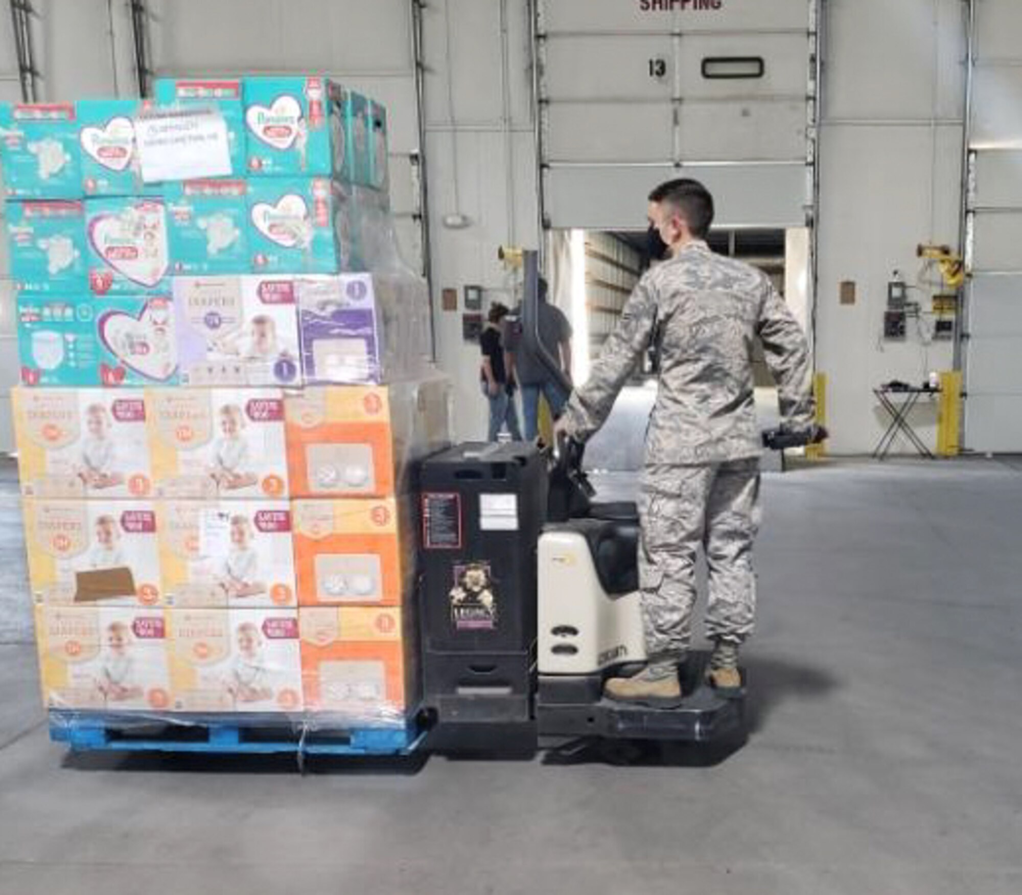 Airman operating fork lift with pallet of supplies