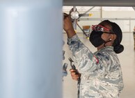 Female mechanic removes bolt from aircraft.