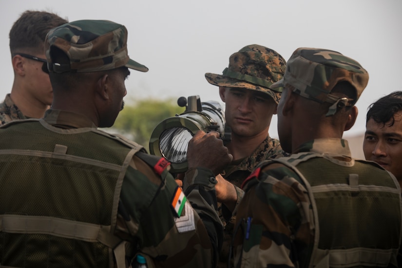 Multiple service members gather around a shoulder-mounted weapon.