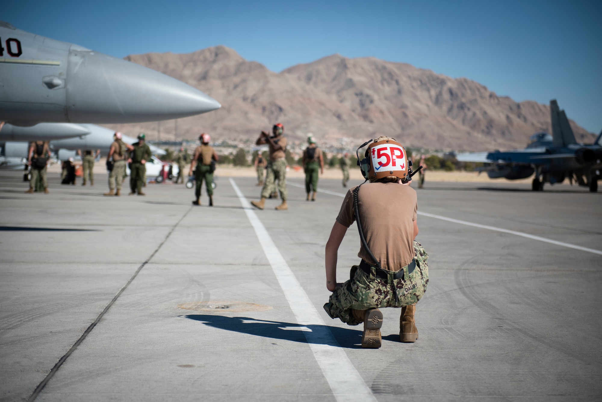 Airman bends down on the flight line.
