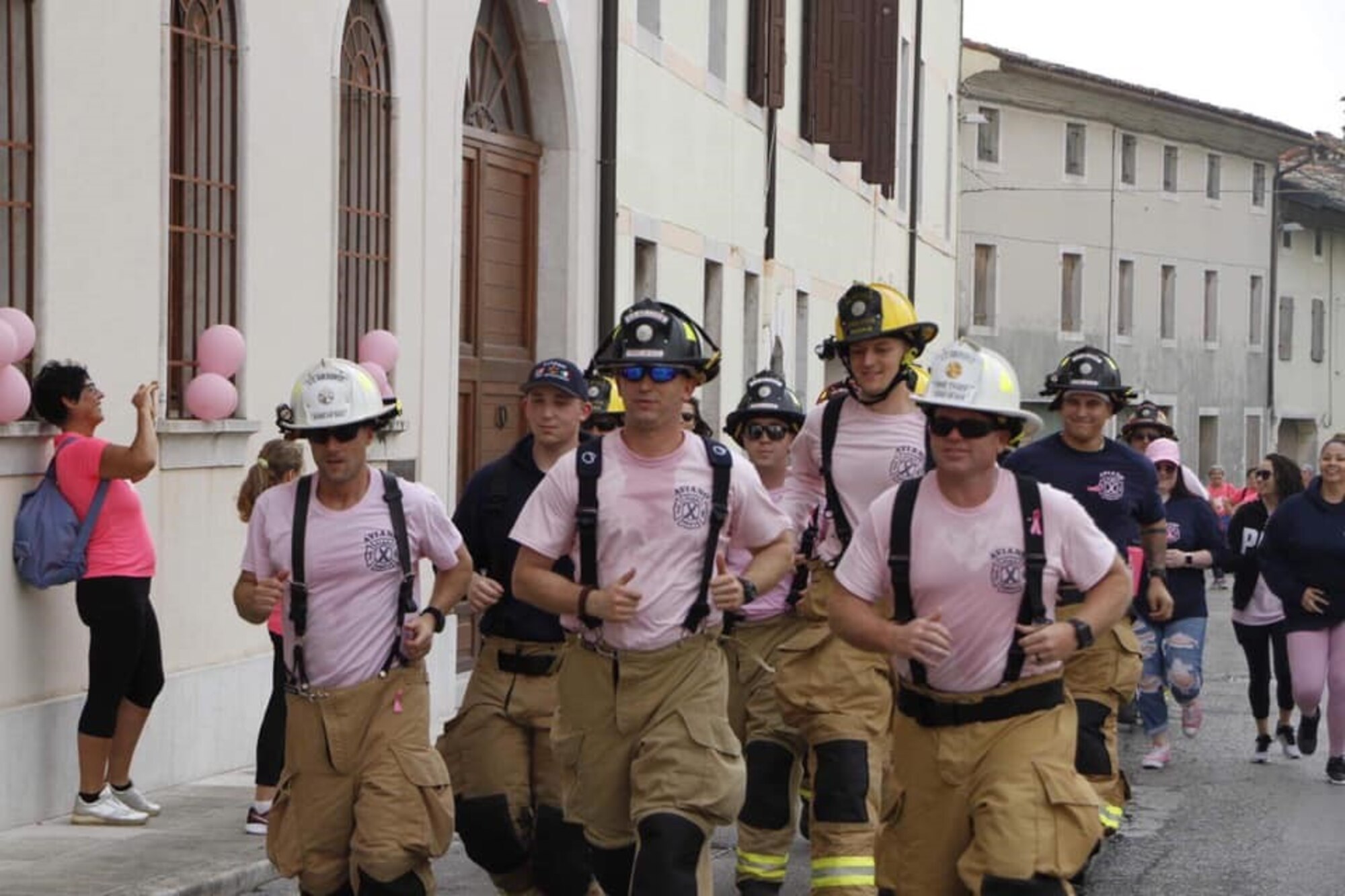 Members of the 31st Civil Engineer Squadron participate in a breast cancer awareness event in the Aviano Square, Italy, Oct. 13, 2019. The Aviano Firefighter Association sold shirts and hoodies to donate money to a local hospital for breast cancer awareness month. (Courtesy photo)
