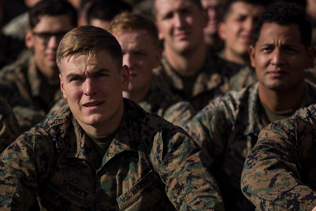 Multiple individuals in military uniform are seated near each other.